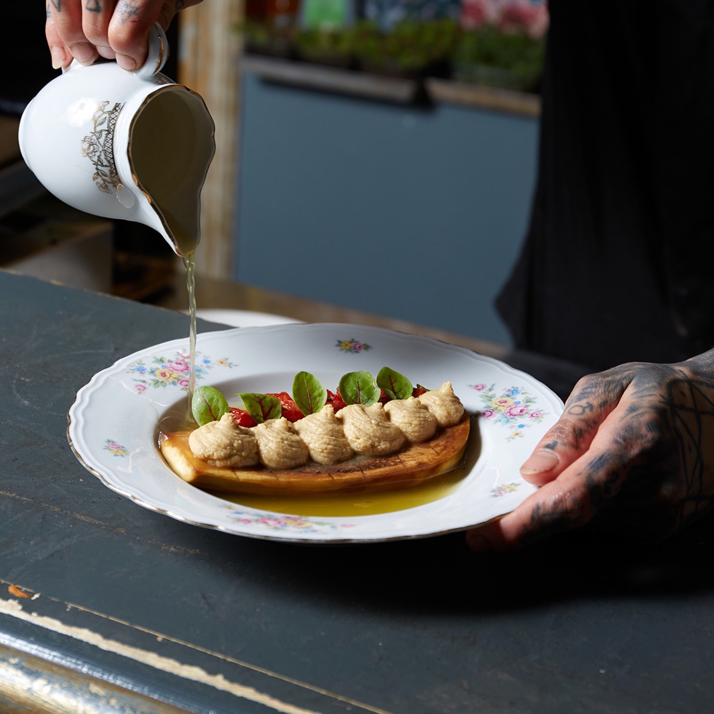 Chef pouring sauce over a plated dish at Brut Merate