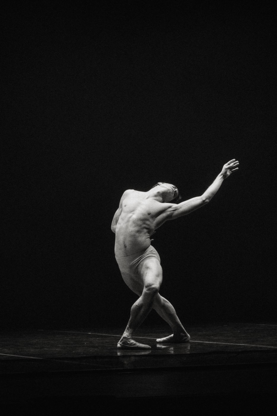 Dancer extending an arm on a dark stage