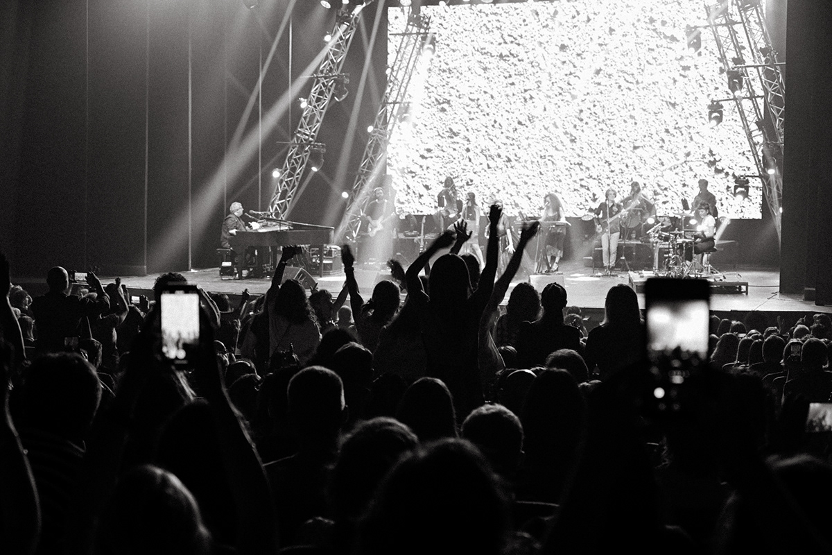 Gli smartphone del pubblico incorniciano il palco pieno di coriandoli